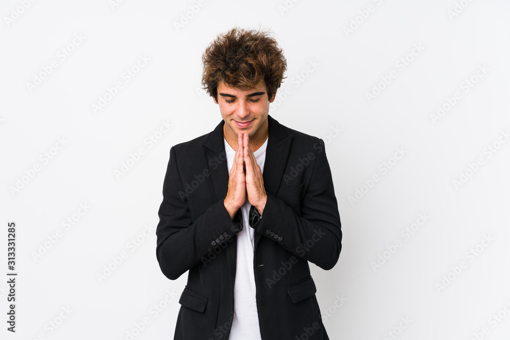 Young caucasian business man against a white background isolated holding hands in pray near mouth, feels confident. Young caucasian business man against a white background isolated holding hands in pray near mouth, feels confident.
