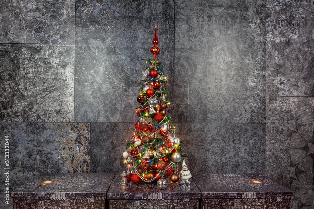 Decorated Christmas tree on a dark base, with a dark background.