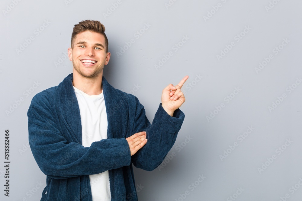 Young caucasian man wearing pajama smiling cheerfully pointing with forefinger away. Young caucasian man wearing pajama smiling cheerfully pointing with forefinger away.