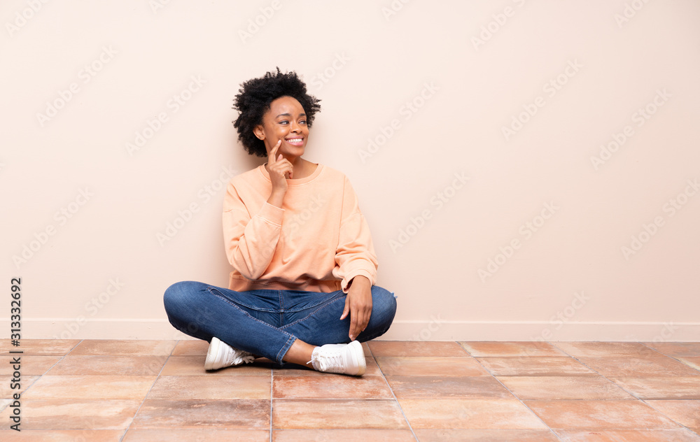 African american woman sitting on the floor thinking an idea while looking up African american woman sitting on the floor thinking an idea while looking up