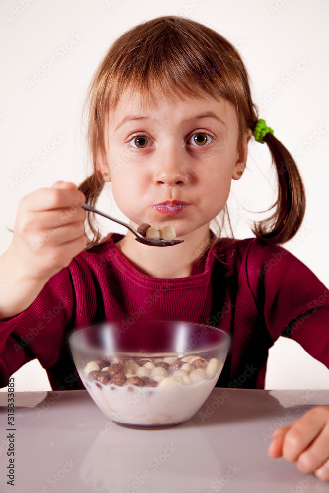 Funny image of cute little child girl having breakfast muesli with milk. Healthy food, eating, happy childhood concept. Funny image of cute little child girl having breakfast muesli with milk. Healthy food, eating, happy childhood concept.