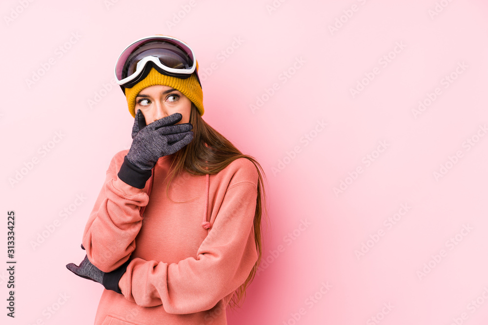 Young caucasian woman wearing a ski clothes isolated thoughtful looking to a copy space covering mouth with hand. Young caucasian woman wearing a ski clothes isolated thoughtful looking to a copy space covering mouth with hand.