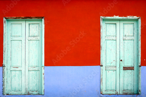 close up on colorful mediterranean style facade with two wooden doors as background