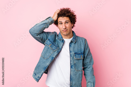 Curly mature man wearing a denim jacket against pink background being shocked, she has remembered important meeting. © Asier