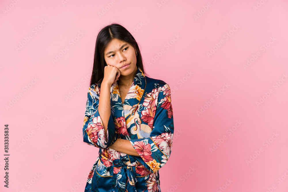 Obraz premium Young asian woman wearing a kimono pajamas who feels sad and pensive, looking at copy space.