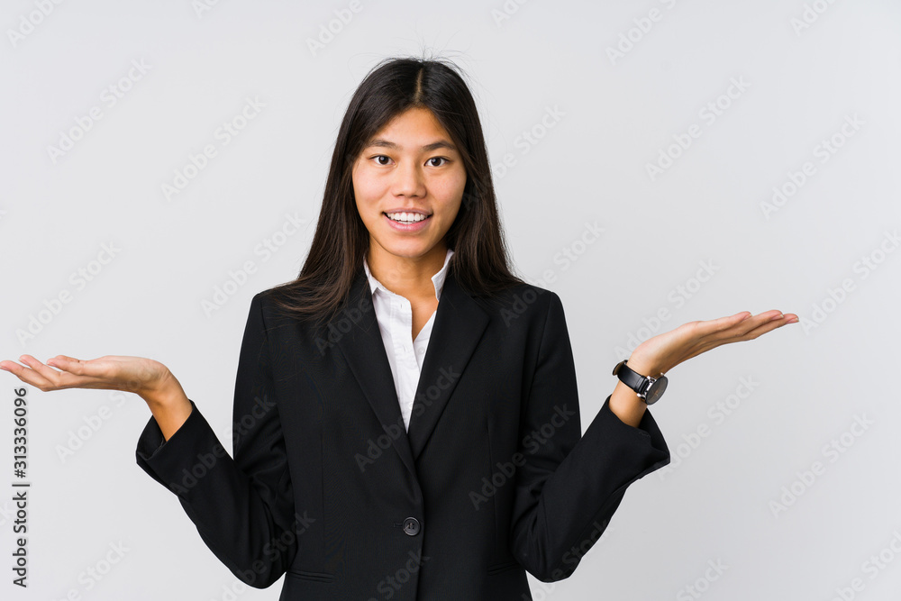 Young asian business woman makes scale with arms, feels happy and confident. Young asian business woman makes scale with arms, feels happy and confident.