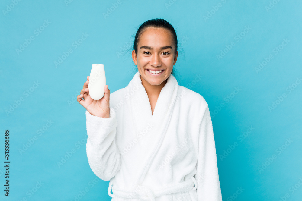 Young mixed race indian holding a moisturizer happy, smiling and cheerful.