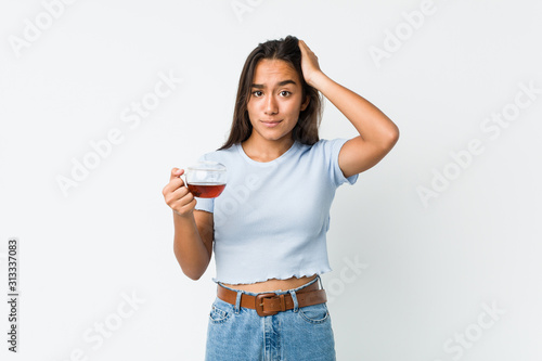 Young mixed race indian holding a tea cup being shocked, she has remembered important meeting. © Asier