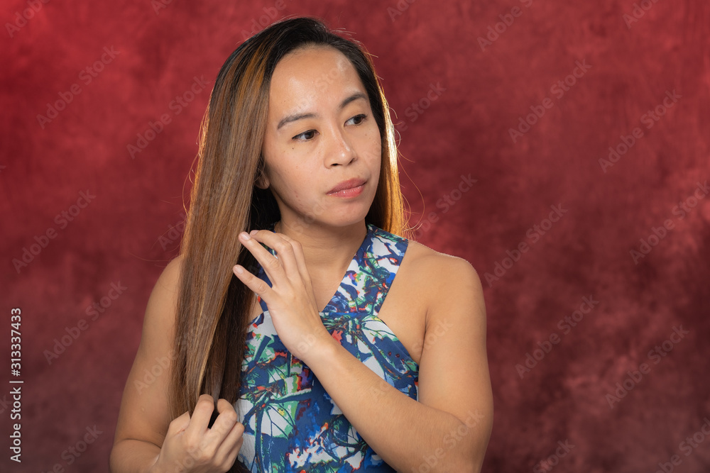 Fototapeta premium Young Filipina woman posing for studio headshots. Backlit on red and blue background
