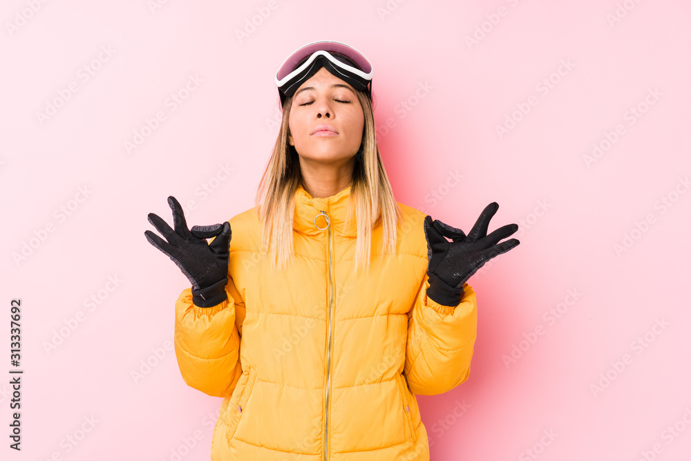 Young caucasian woman wearing a ski clothes in a pink background relaxes after hard working day, she is performing yoga. Young caucasian woman wearing a ski clothes in a pink background relaxes after hard working day, she is performing yoga.