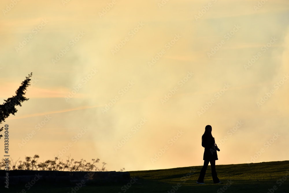 Silhouette of a young photographer on a hill contemplating a foggy winter sunset