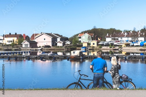 Old couple with bikes sitting on bench by the water. 