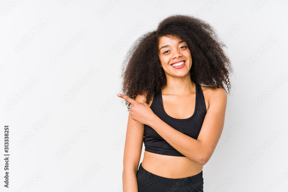 Young african american sporty woman smiling and pointing aside, showing something at blank space. Young african american sporty woman smiling and pointing aside, showing something at blank space.