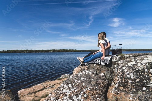 Young couple sitting beside the water holding eachother.  