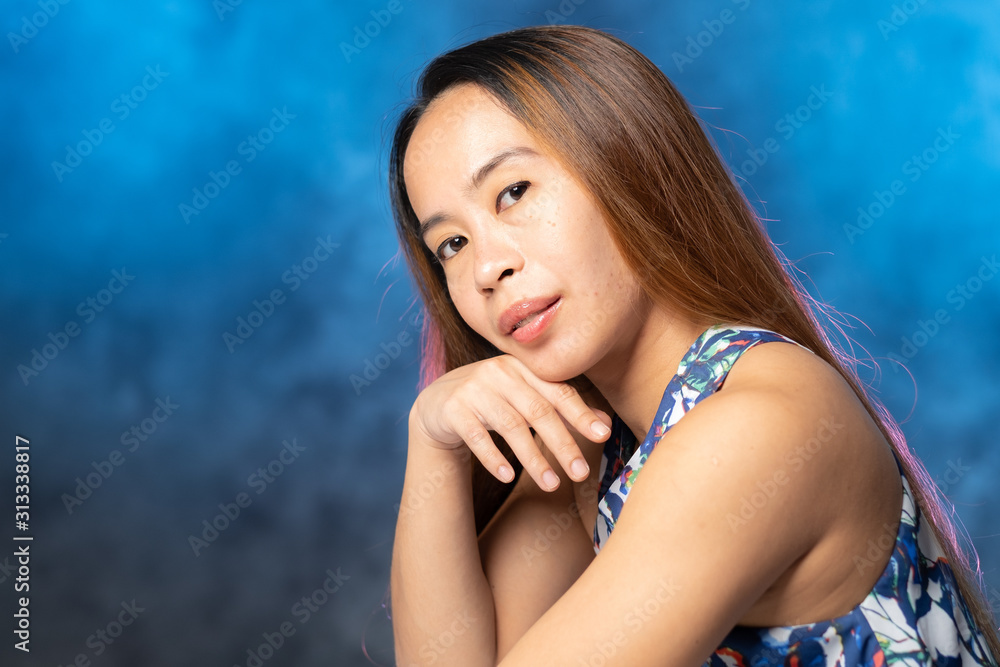 Young Filipina woman posing for studio headshots. Backlit on red and blue background Young Filipina woman posing for studio headshots. Backlit on red and blue background