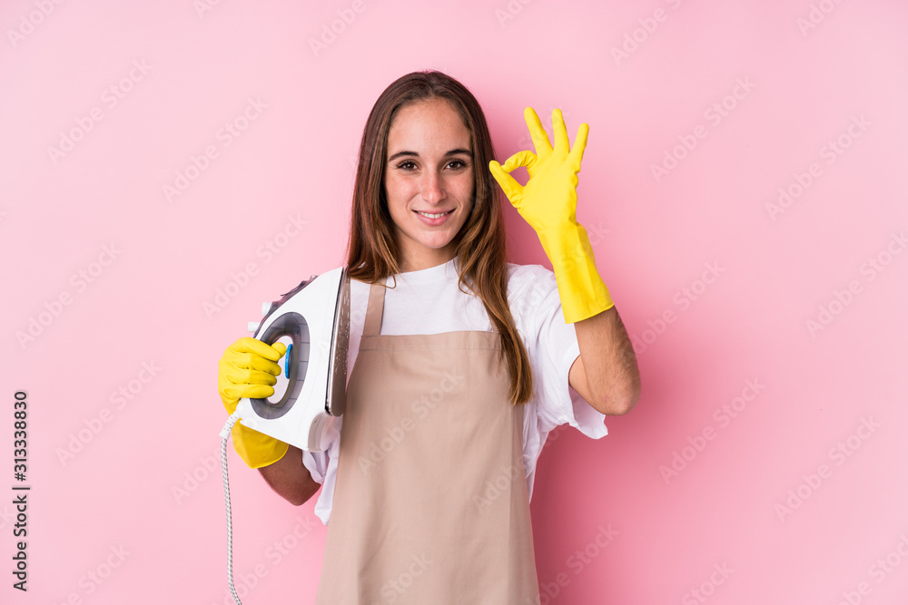 Young caucasian woman with clothes iron isolated cheerful and confident showing ok gesture. Young caucasian woman with clothes iron isolated cheerful and confident showing ok gesture.
