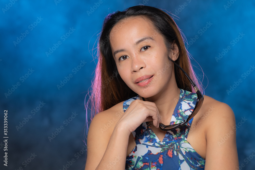 Young Filipina woman posing for studio headshots. Backlit on red and blue background Young Filipina woman posing for studio headshots. Backlit on red and blue background