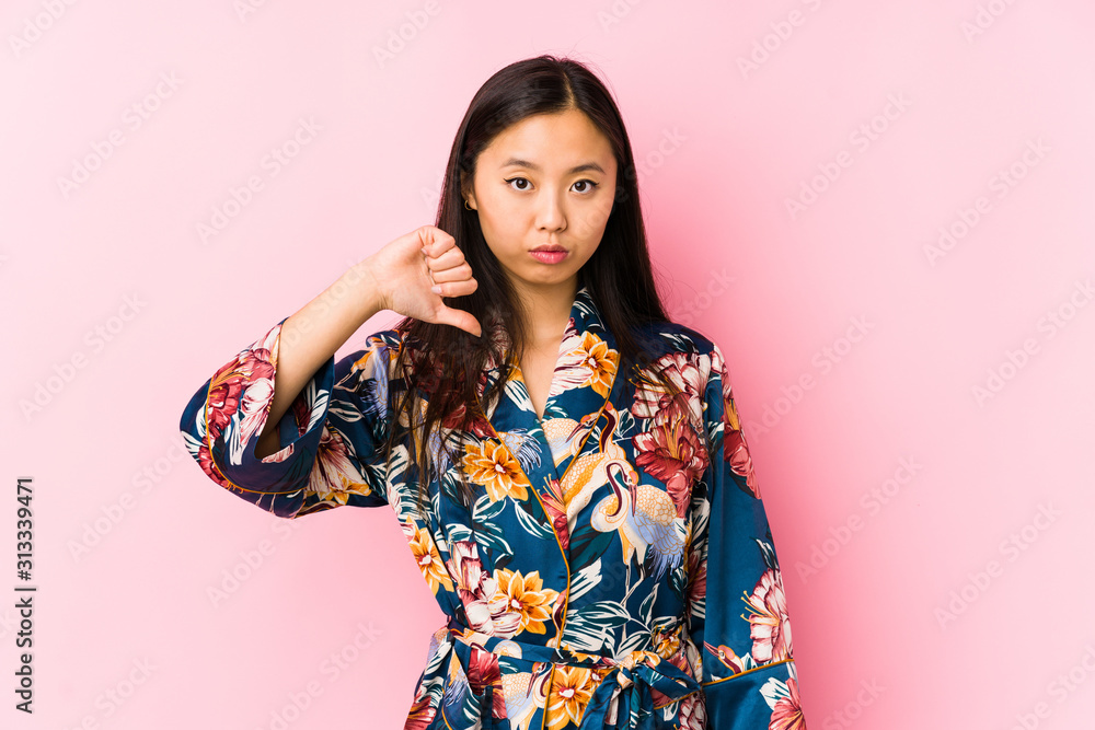 Young chinese woman wearing a kimono pajama isolated showing a dislike gesture, thumbs down. Disagreement concept. Young chinese woman wearing a kimono pajama isolated showing a dislike gesture, thumbs down. Disagreement concept.