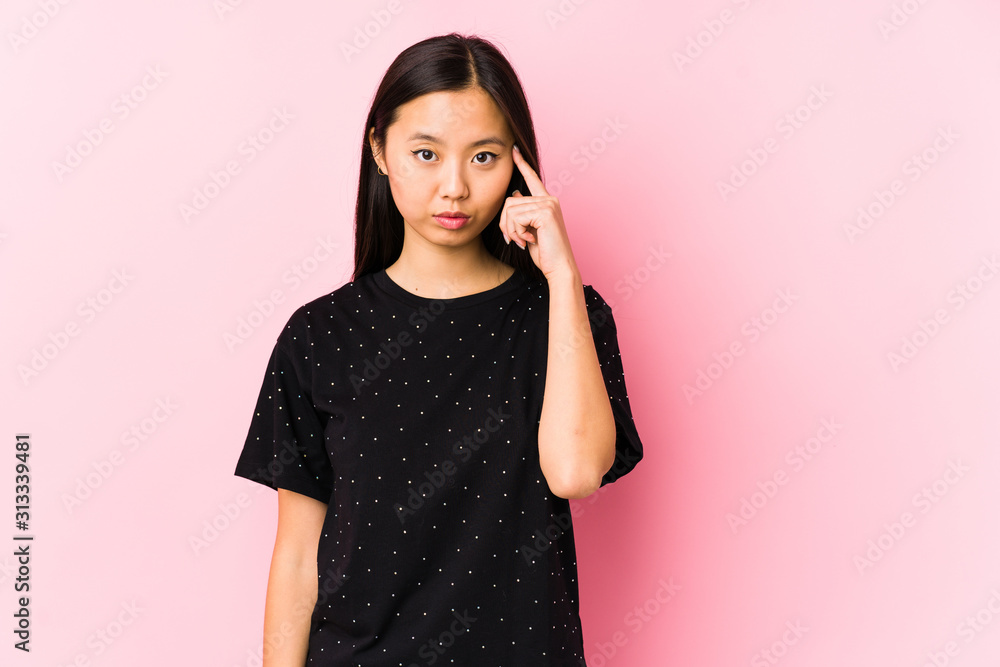 Young asian woman wearing elegant clothes isolated pointing temple with finger, thinking, focused on a task. Young asian woman wearing elegant clothes isolated pointing temple with finger, thinking, focused on a task.