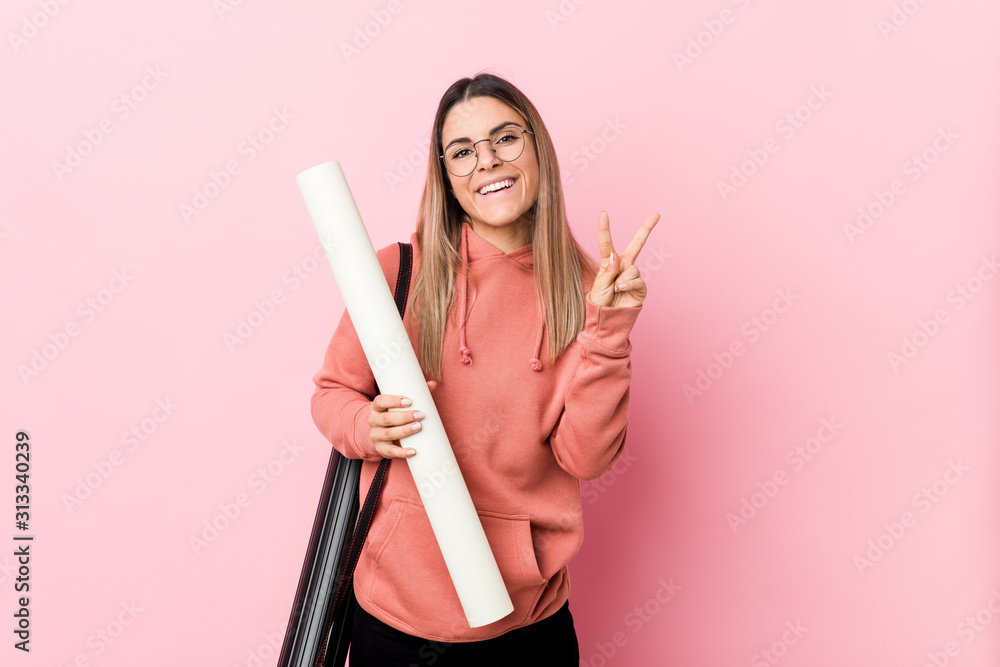 Young woman studying architecture joyful and carefree showing a peace symbol with fingers. Young woman studying architecture joyful and carefree showing a peace symbol with fingers.