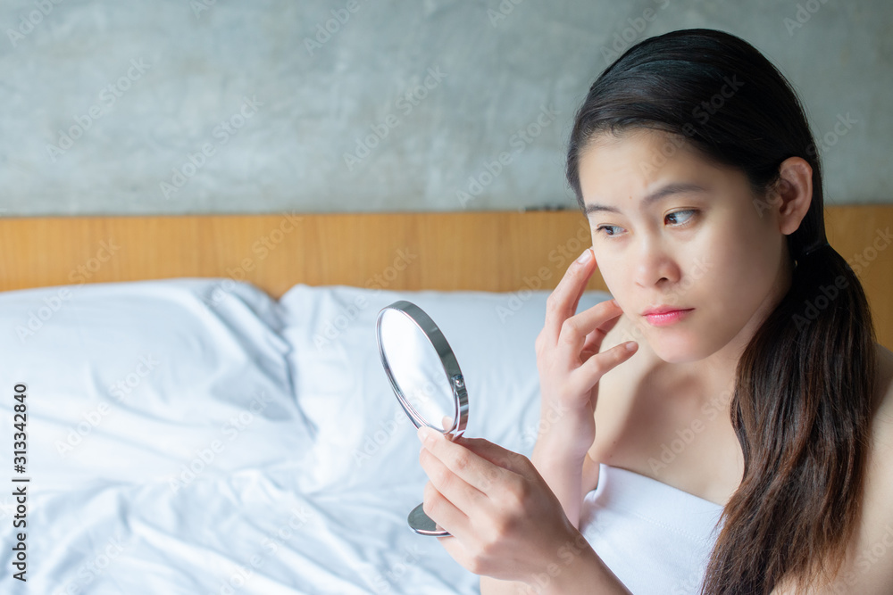 Portrait of Asian woman worry about her face when she saw the problem of acne and scar by the mini mirror. Conceptual shot of Acne & Problem Skin on female face. Portrait of Asian woman worry about her face when she saw the problem of acne and scar by the mini mirror. Conceptual shot of Acne & Problem Skin on female face.