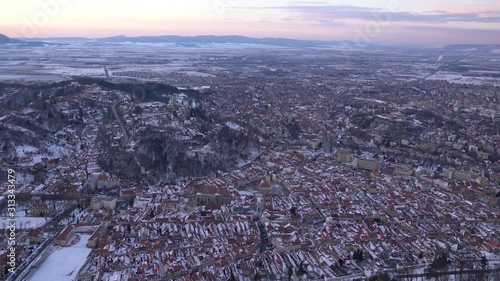 Brasov, Transylvania. Romania. Panoramic 4K Video Footage view of the old town and Council Square. Aerial twilight city`s skyline in a cold December. photo