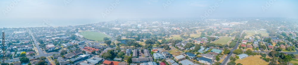 Wide aerial panorama of suburbs covered in smoke haze from bush fires in Gippsland, Victoria, Australia