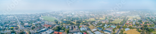 Wide aerial panorama of suburbs covered in smoke haze from bush fires in Gippsland, Victoria, Australia