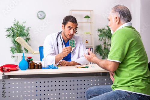 Old man visiting young male doctor gastroenterologist