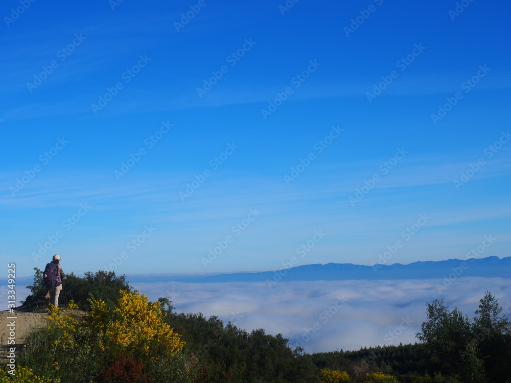 Obraz premium Amazing sea of clouds with Pilgrim on the road to Santiago de Compostela, Camino de Santiago, Way of St. James, Journey from Foncebadon to Ponferrada, French way, Spain