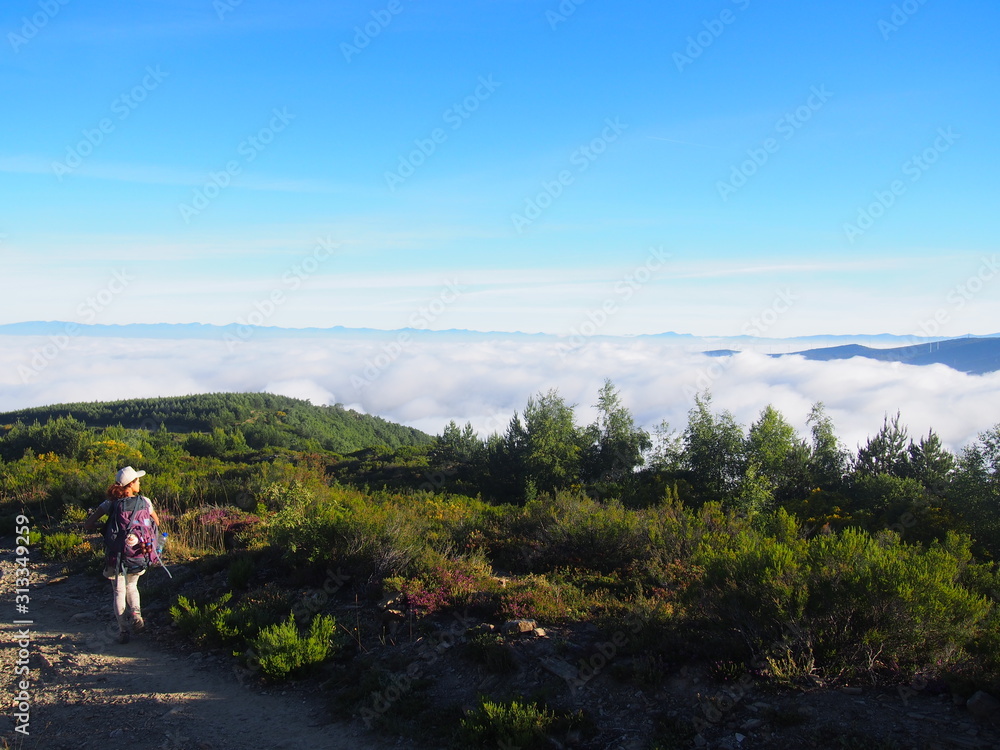 Amazing sea of clouds with Pilgrim on the road to Santiago de Compostela, Camino de Santiago, Way of St. James, Journey from Foncebadon to Ponferrada, French way, Spain