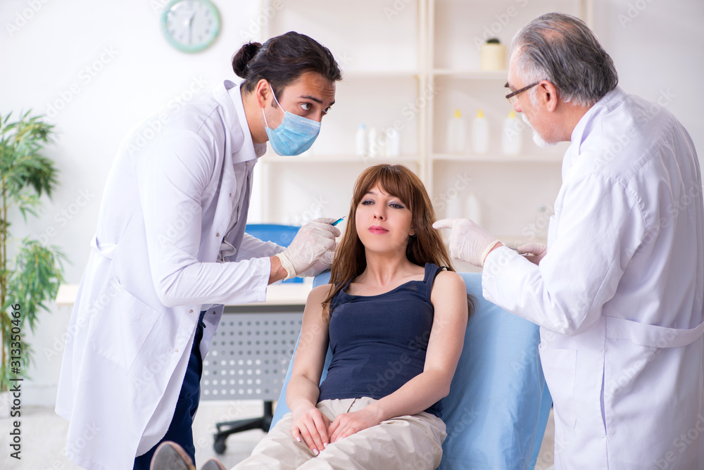 Two male doctors and young woman in plastic surgery concept Two male doctors and young woman in plastic surgery concept