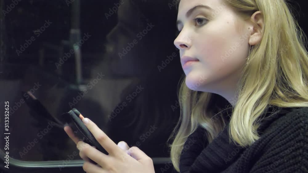 Young Woman on train tram metro at night using mobile phone device Young Woman on train tram metro at night using mobile phone device