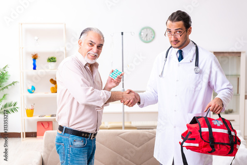 Young male doctor visiting old patient at home