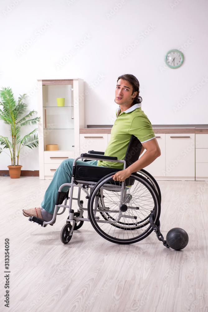 Young male invalid in wheel-chair suffering at home Young male invalid in wheel-chair suffering at home