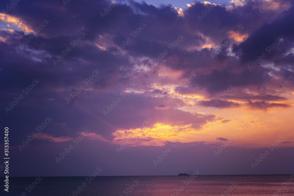 Bright magical sunset over the sea, golden purple and pink tones. Fluffy clouds