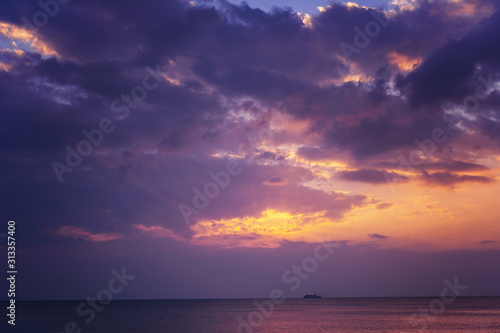 Bright magical sunset over the sea  golden purple and pink tones. Fluffy clouds