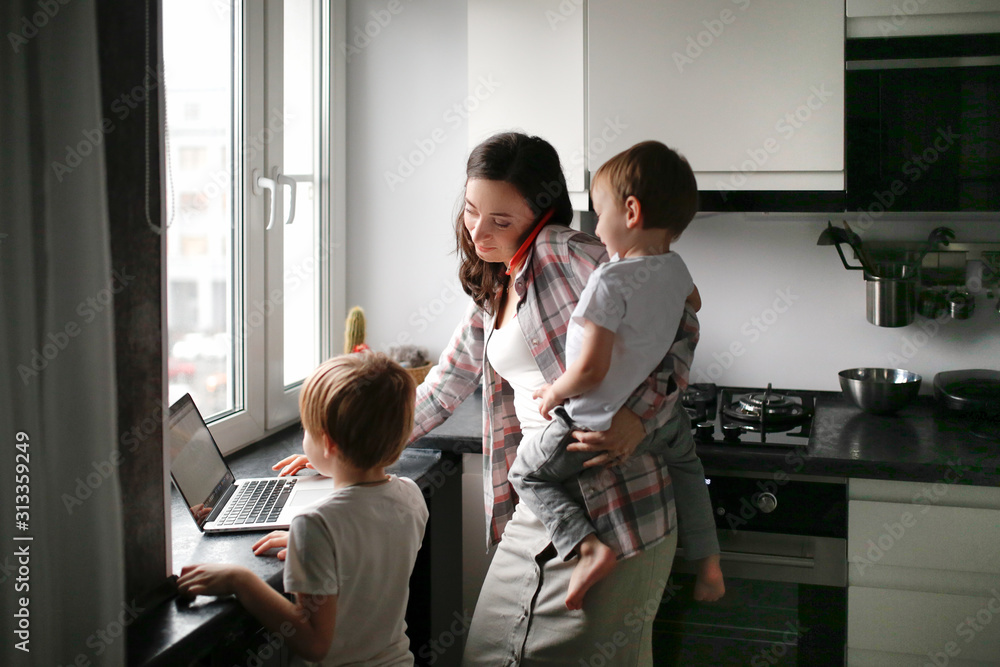 Busy mom with two children works on laptop kitchen Stock Photo Adobe Stock