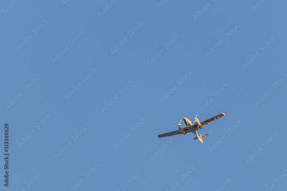 a twin-engined small airplane flies in the blue cloudless sky a twin-engined small airplane flies in the blue cloudless sky
