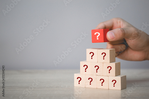 Hand arranging wood block stacking with icon question mark,thinking with question mark concept.