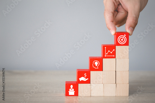 Hand arranging wood block stacking with icon arrow and business,targeting the business concept. photo