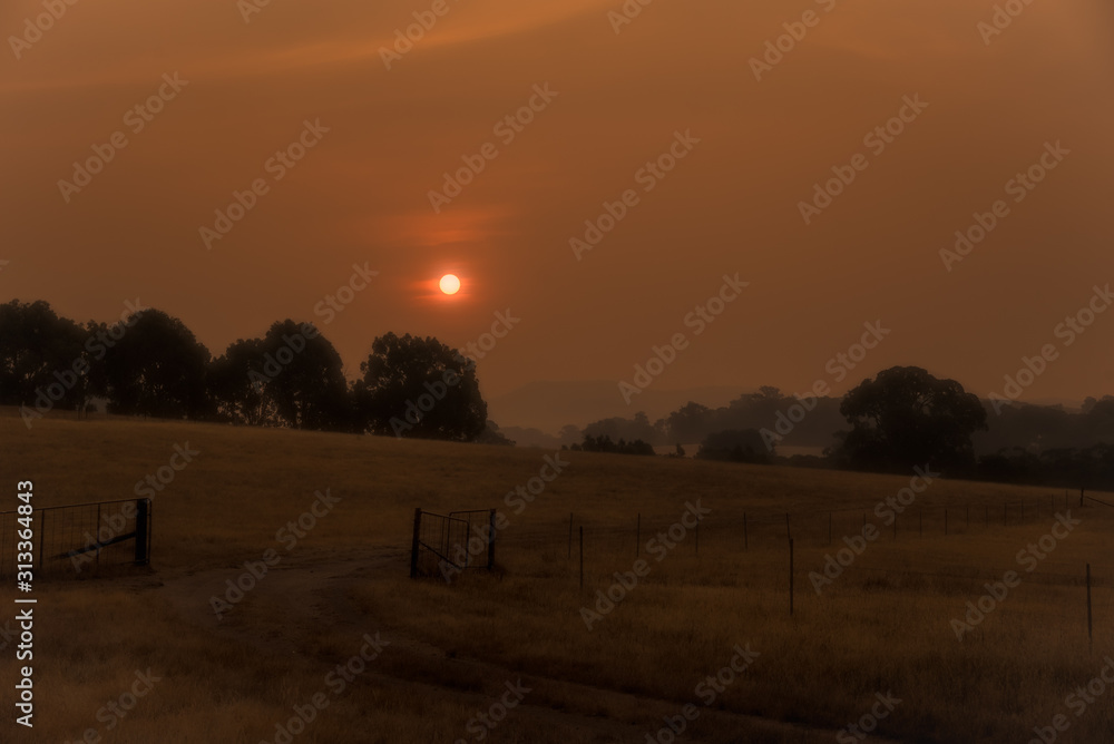 Smokey rural landscape with bright red sun caused by fires in  Victoria