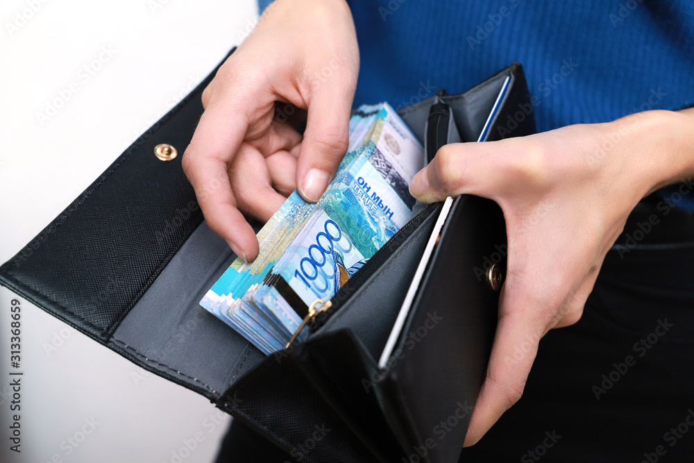 Puts the money in her wallet. Banknote of ten thousand tenge. Puts the money in her wallet. Banknote of ten thousand tenge.