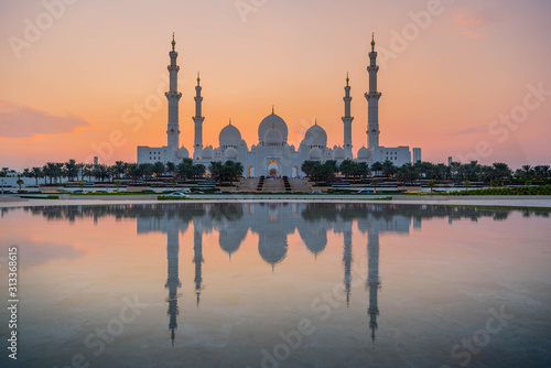 bu Dhabi, UAE, United Arab Emirates: Stunning view of Abu Dhabi Sheikh Zayed Mosque (also known as Grand Mosque) at dusk, reflection in water, illuminated at sunset, golden blue hour