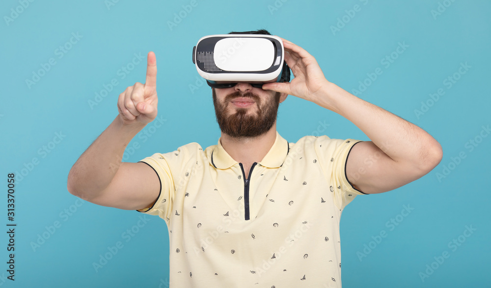 Young man using VR glasses headset trying to touch objects in virtual reality. Isolated white background. Young man using VR glasses headset trying to touch objects in virtual reality. Isolated white background.