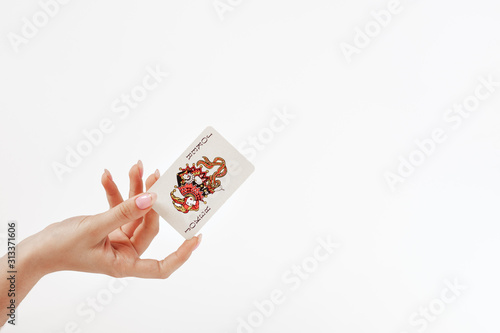 female hand holds a playing card Joker from a card deck of cards on the white background,  concept of good luck, victory, risk photo