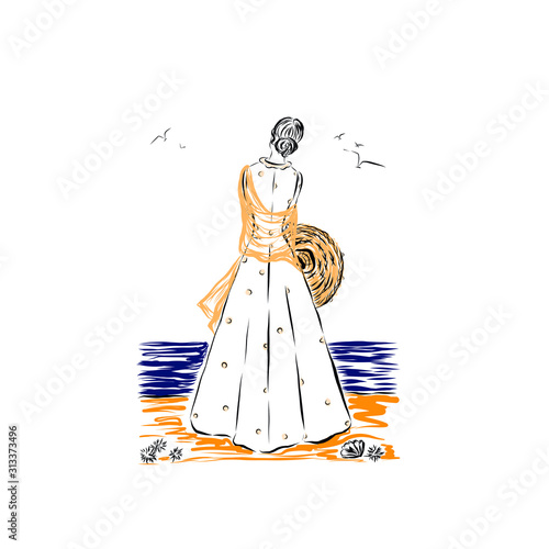 woman stands with her back and looks at the sea holding a hat in her hands