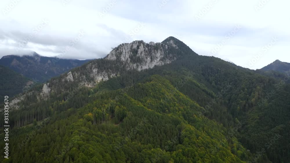 Aerial, reverse, drone shot, over forest, away from a rocky limestone peak, on a cloudy, summer day, in Grunau im Almtal, Salzkammergut, Upper Austria Aerial, reverse, drone shot, over forest, away from a rocky limestone peak, on a cloudy, summer day, in Grunau im Almtal, Salzkammergut, Upper Austria