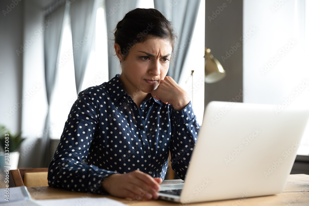 Concerned indian woman look at laptop frustrated about computer problem Concerned indian woman look at laptop frustrated about computer problem