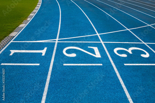 Blue running treadmill track with lane numbers in stadium outdoors.Starting grid of race track at the stadium